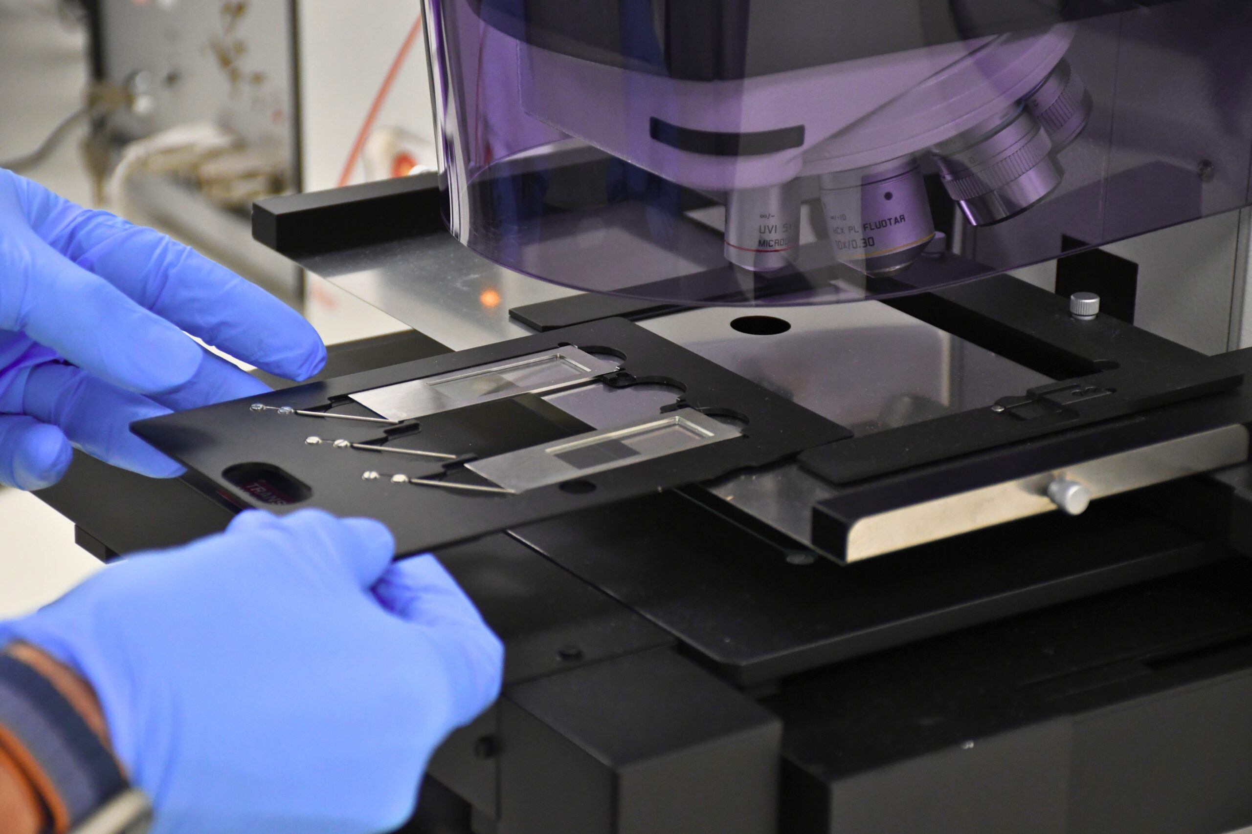 Gloved hands loading laser capture microscope