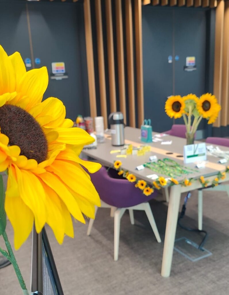 Photograph of sunflower with a table covered with materials in the background