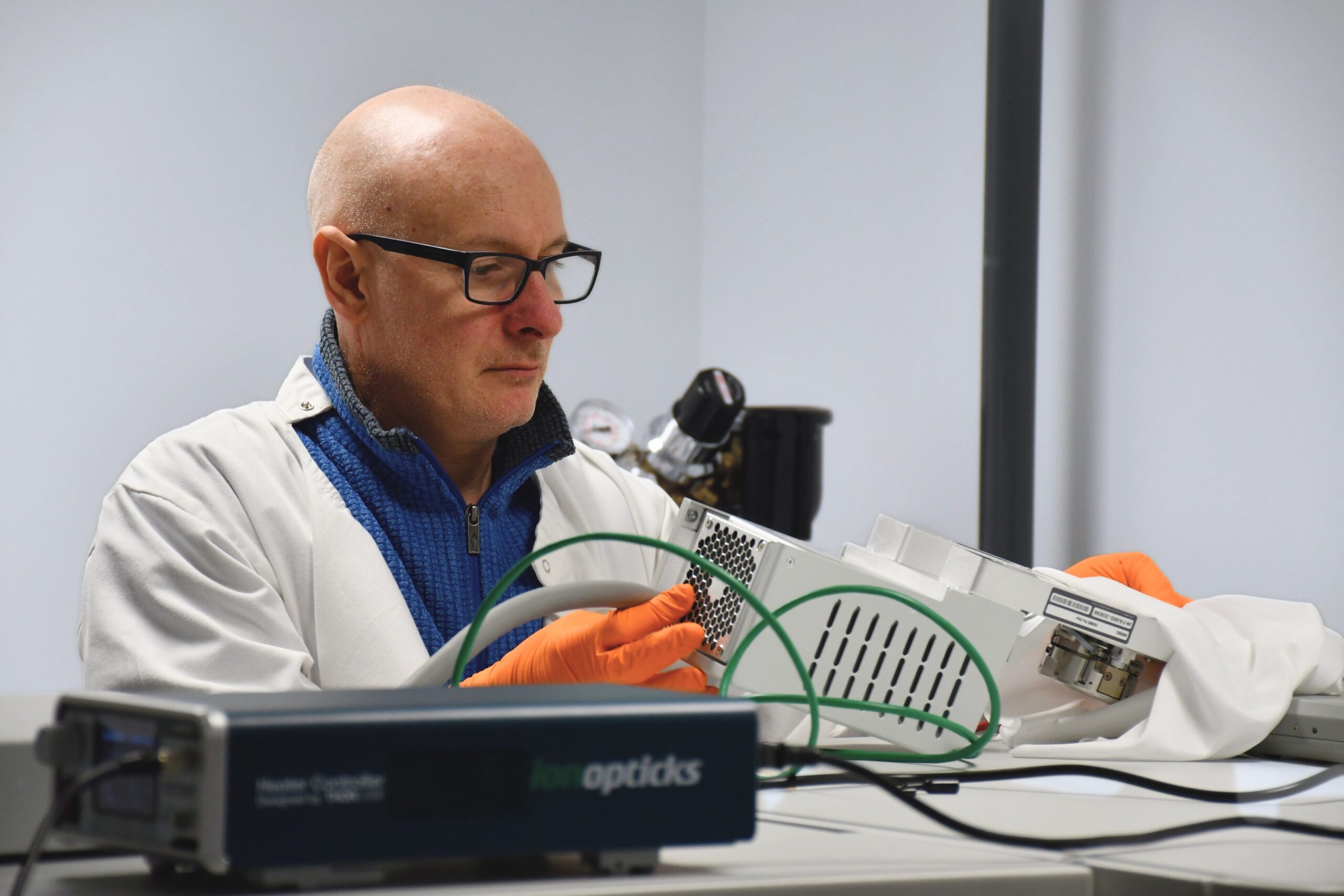 Duncan Smith wearing a lab coat and adjusting mass spectrometry equipment
